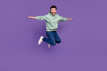 Obraz premium Full size photo of energetic cheerful man jumping arms wings flying isolated on violet color background
