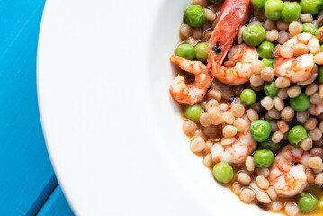 Piatto di deliziosa zuppa di fregula sarda con gamberetti e pisellini primavera, cibo italiano 