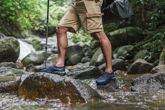 Close up legs of a trekker crossing river in the mountains. travel, hiking, trekking concept.