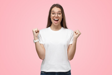 Pretty girl celebrating victory as winner, squeezing fists in expression of happiness and luck