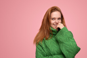 Confident lady touching lips and smiling in pink studio