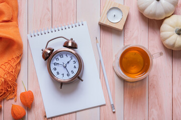 Time Change concept with autumn cozy decor top view on desktop with alarm clock and laptop. Fall back concept.