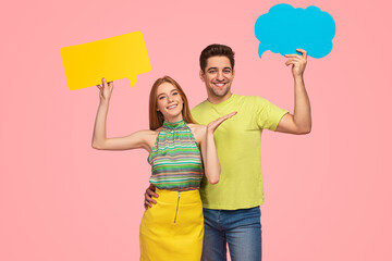 Cheerful young couple smiling and showing speech balloons in studio
