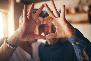 Love, hands and heart sign with senior couple relax and bonding in their home together, cheerful...