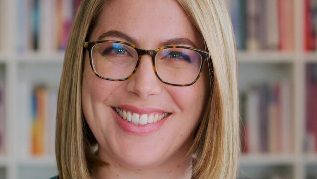Young woman and library portrait with happy expression on face with glasses at books shelf closeup. Professional phd university professor in education facility for research, study and learning.