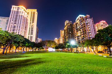 Fototapeta na wymiar Night view of park green space and modern buildings on both sides in downtown Taichung, Taiwan. here is near the National Taichung Theater.