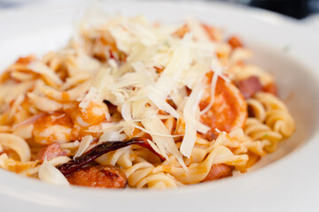 Closeup on chili pepper on pasta spirals with seafood, meat and grated cheese on tomato sauce. Traditional Italian food plate Mexican style