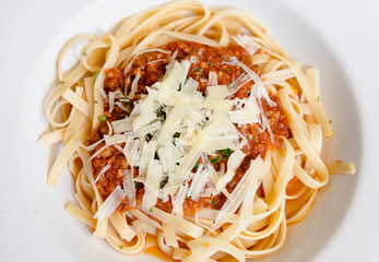Tagliatelle bolognese plate with grated Parmesan cheese view from top. Traditional Italiand food close up