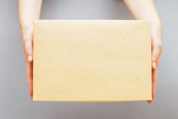 human hands holding delivers carton box on grey background. Delivery and online shopping concept.