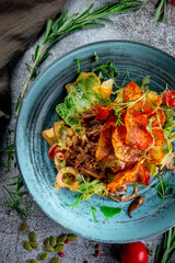 Green salad with fried potato chips, tomatoes, mushrooms and beef with red onion rings and arugula