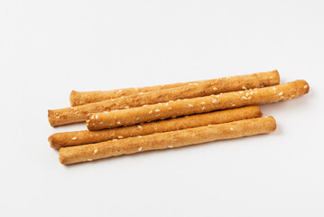 Pile of bread sticks grissini with sesame seeds in white form. Traditional Italian pastry breadsticks isolated  on white background
