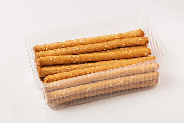 Product bread sticks grissini with sesame seeds in plastic packaging. Traditional Italian pastry breadsticks isolated  on white background