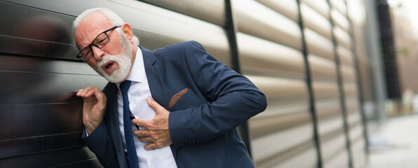 Senior businessman having heart attack in front of the office building