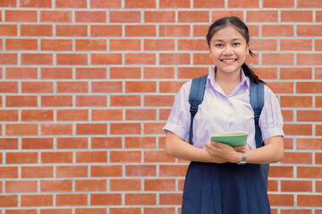 Thai asian school girl teen happy smile in uniform handle book and school bag with copy space