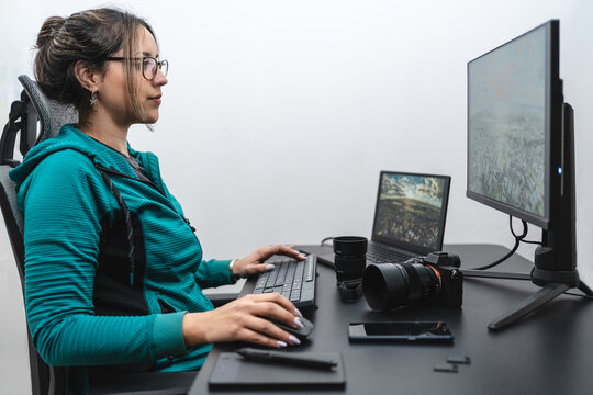 Young Hispanic woman photographer in editing process on her desk