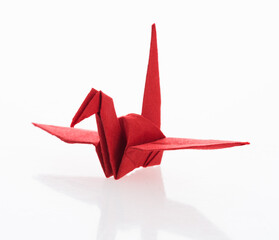 Red origami paper crane on white background © xy