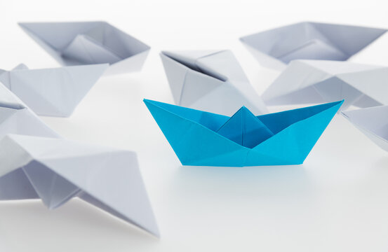 Blue paper boat and a lot of sinking ships