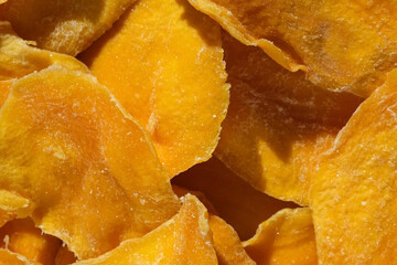 Dried mango slices close-up on a white. Top view. Closeup. Mango chips background. Dehydrated crispy fruit slices, pieces. Heap of sun-dried yellow fruit. Healthy meal. Top view, flat lay.