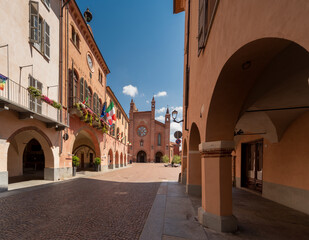 Alba, Langhe, Piedmont, Italy - August 16, 2022: via Cavour with medieval arcades and the Town Hall with flowered balconies, in the background Cathedral of San Lorenzo in Piazza Duomo