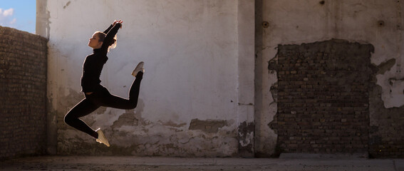 Ballerina dancing in an abandoned building on a sunny day