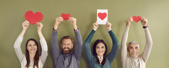 Group of four happy, cheerful people of different ages standing against green color studio...