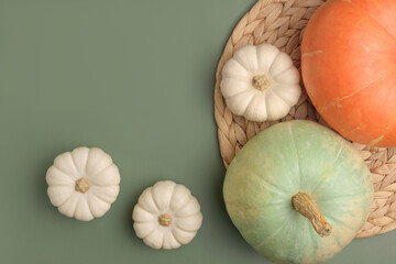 Autumn composition. Various pumpkins on olive green Background. Flat lay, top view, copy space. Nordic, hygge, cozy home concept. Thanksgiving fall decoration. Halloween Modern Invitation Mock up