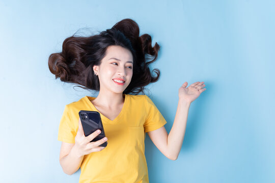 Image of young Asian woman lying on background