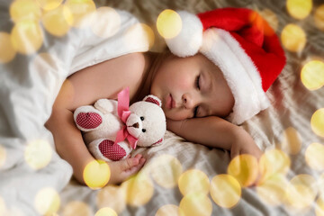 Cute Sleeping Young Boy in Santa Claus Hat Lying in Bed at Home. Christmas Light. Winter Holiday Concept. Dream. Toddler Baby Celebrating Christmas. Merry Xmas, Happy New Year. Funny Little Child.