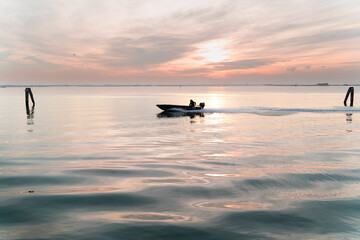 Fototapeta premium early morning fisher riding his boat to catch some fish