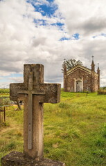 An old stone cross and a Catholic chapel