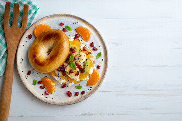 Toasted bagel with orange marmalade, cream cheese, tangerine, kiwi, banana and pomegranate. vegan breakfast. Superfood vegan brunch.