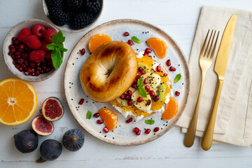 Toasted bagel with orange marmalade, cream cheese, tangerine, kiwi, banana and pomegranate. vegan breakfast. Superfood vegan brunch.