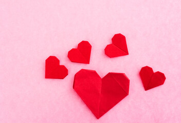 Red origami hearts on pink background