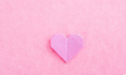 Pink origami heart on pink background