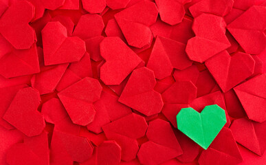 Green origami heart on red origami hearts