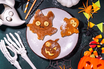 Halloween creative kids breakfast. Cute homemade pancakes in the shape of Halloween holiday symbols - bat, jack pumpkin, ghost, made by cookie cuttings