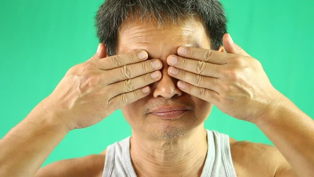 Thai man is closing eyes  ears nose and mouth with green background, in studio  Chiangmai  Thailand.