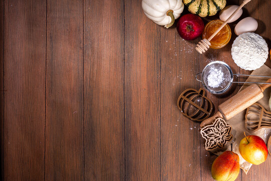 Autumn baking flat lay with pie ingredients, cookie cutters in the shape of a leaf, pumpkin, symbols of autumn, pumpkins and apples on a dark cozy wooden background copy space