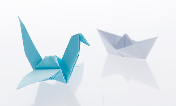 Origami boat and crane on white background