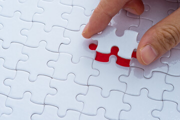 Hand putting the last piece of white jigsaw puzzle