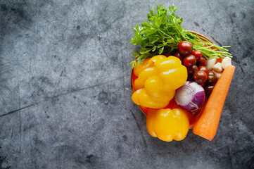 Vegetables on a plate, yellow peppers, onions, carrots and cherry tomatoes, top view, space for text