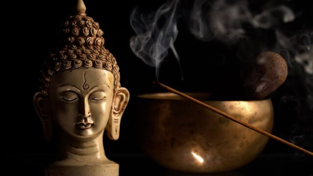 Burning incense stick in the background of buddha and tibetan bowl for meditation and mantra