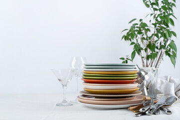 Set of colorful tableware with plates, cutlery and glasses with holiday decorations on dining...