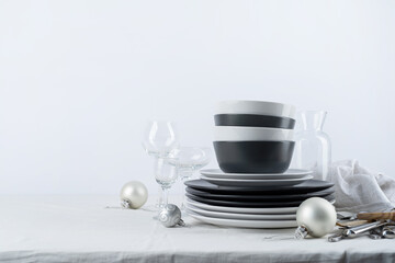 Set of black and white tableware with plates, cutlery and glasses with holiday decorations on dining table, copy space