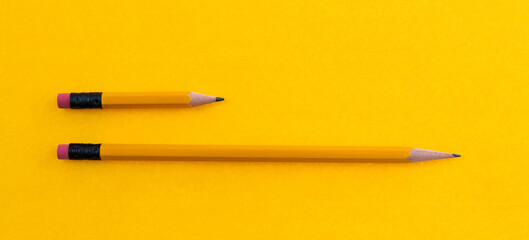 Long and short pencils on yellow background