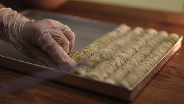 Dessert stick rolls on a row prepared to bake on pastry shop, slow motion shot