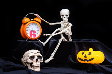 A skeleton waking up, crawling out of the grave, and turning off an orange alarm clock, a pumpkin...
