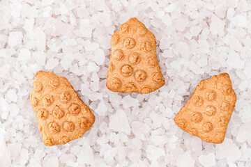 Top view of Christmas bells shaped cookies on background of decorative ice pieces.