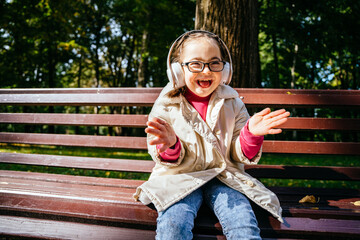 Beautiful little girl in eyeglasses with down syndrome smiling and looking into camera laughing and...