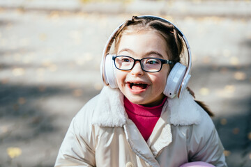 Happy disability kid outdoor portrait. Special need child happy time to use headphones.
